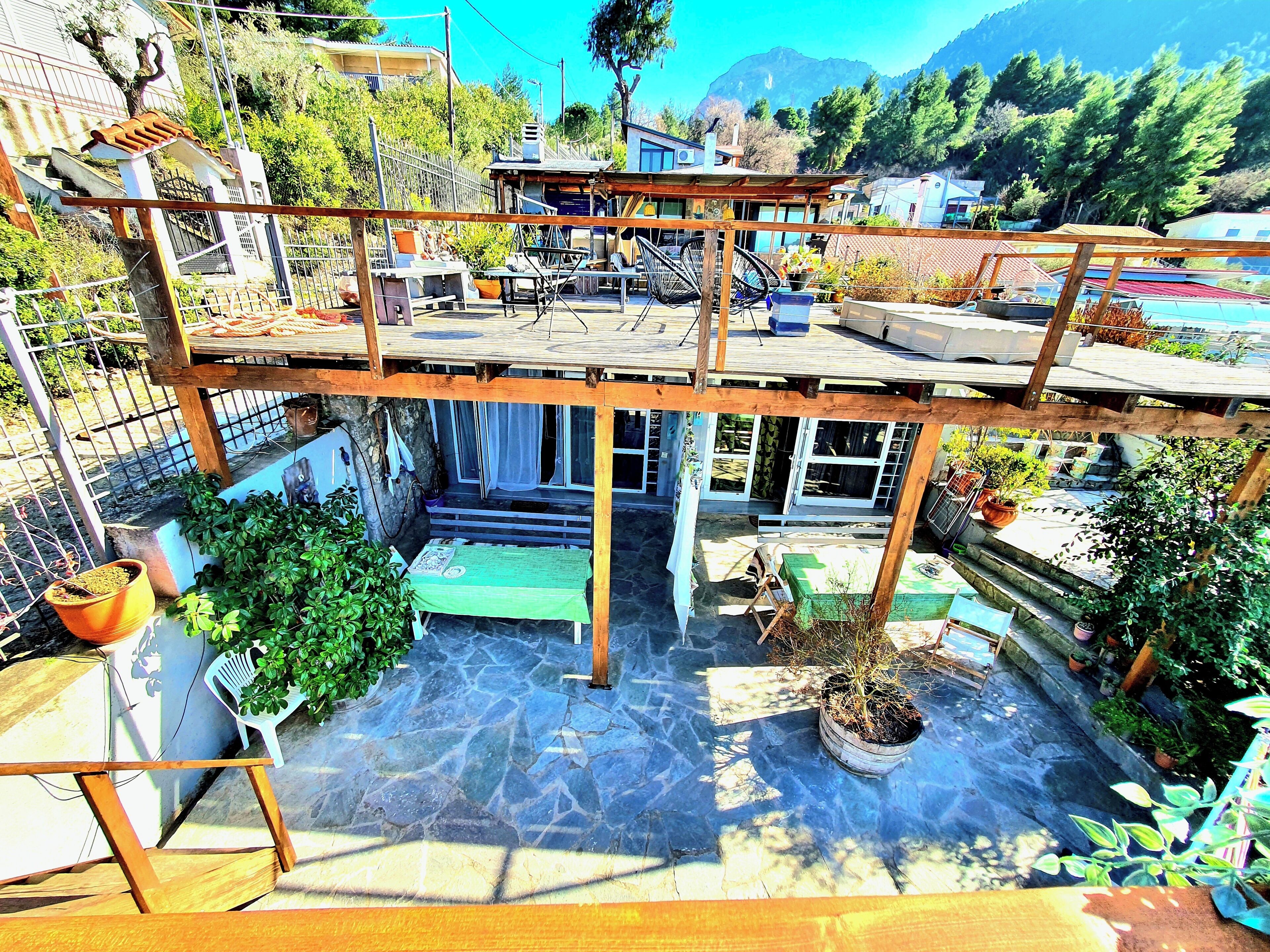 A two-story building with a patio area, outdoor seating, and potted plants.