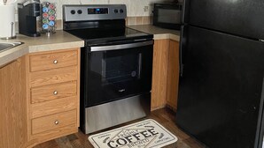 Een keuken met houten kastjes, een zwarte koelkast, een roestvrijstalen oven en een koffiezetapparaat.