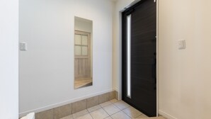 A hallway with a dark sliding door, a light-colored tiled floor, and a small mirror on the wall.