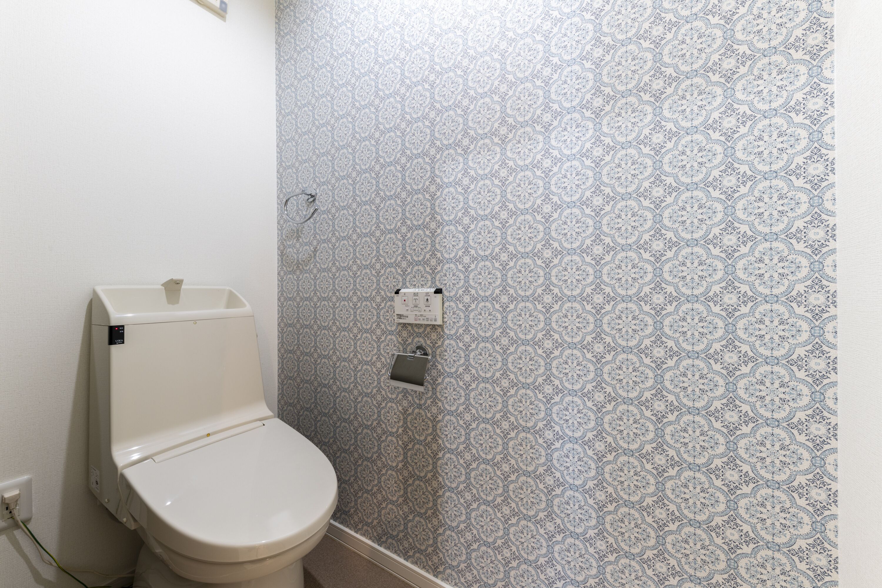 Ein Badezimmer mit Toilette, einem Wand-Spülknopf und einem Papierhandtuchspender.