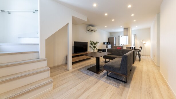 A modern living room with a flat-screen TV, a sofa, and a dining area.
