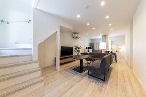 Una sala de estar moderna con una televisión de pantalla plana, un sofá y un comedor.