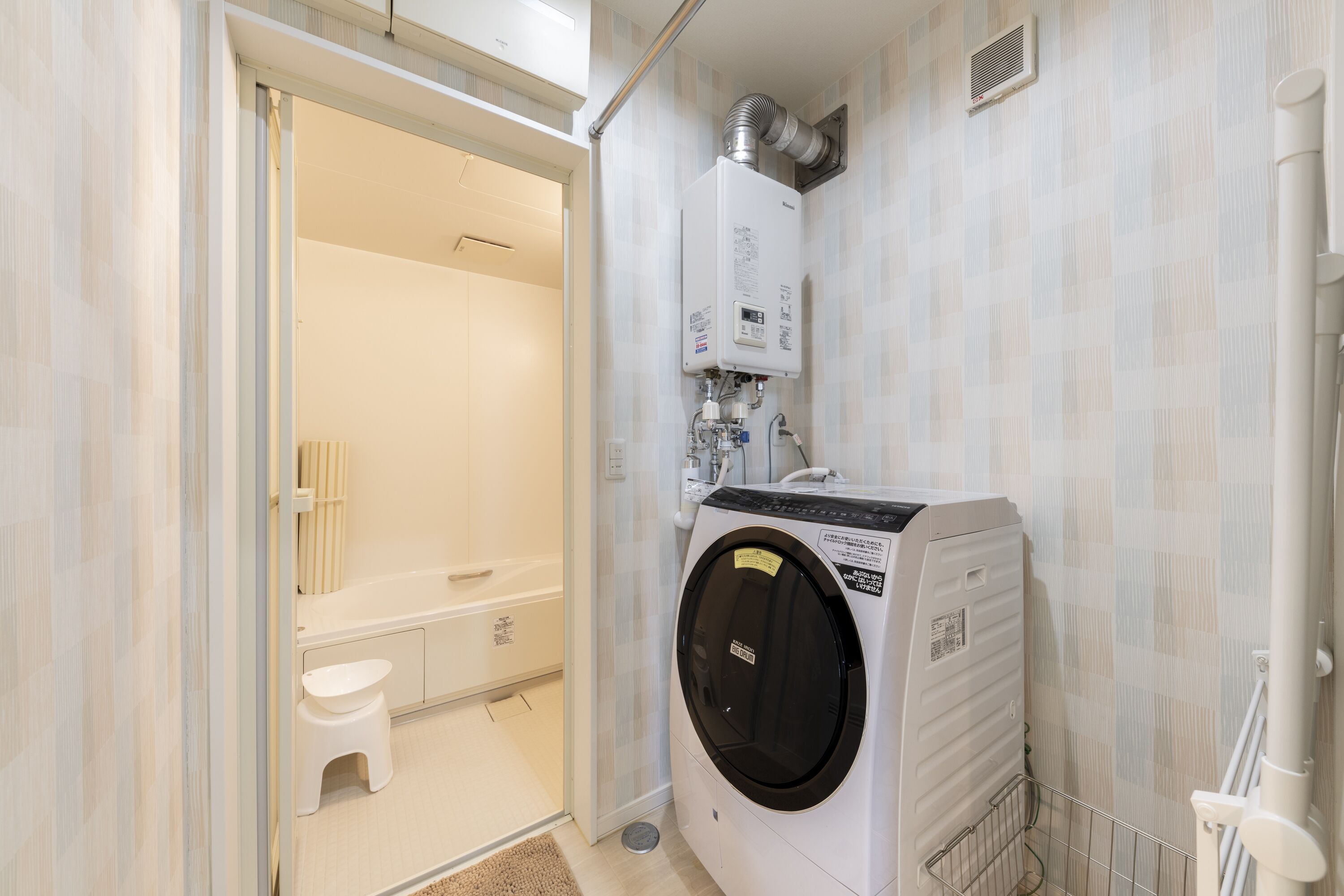 Une petite buanderie comprenant un lave-linge, un sèche-linge et un petit tabouret.