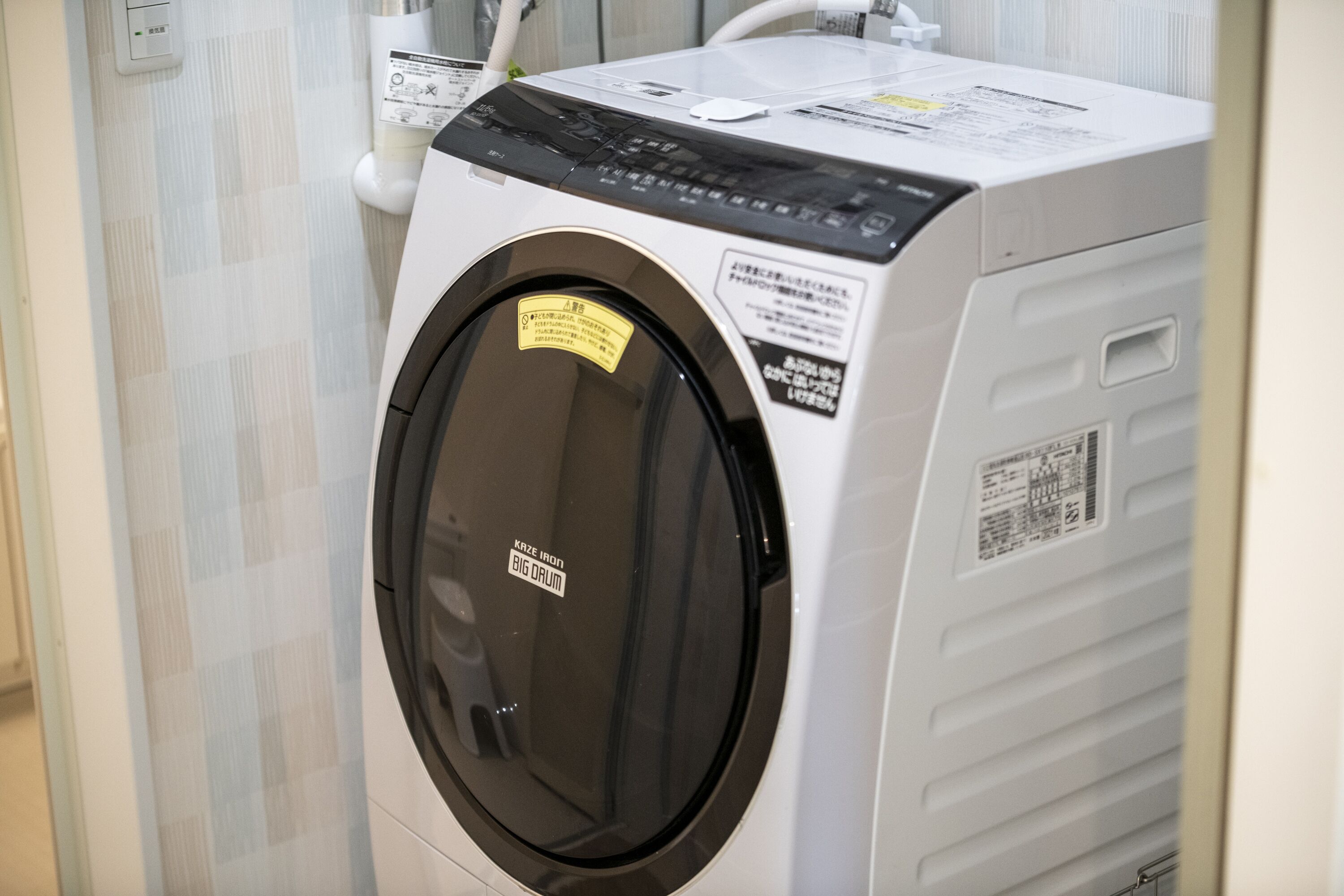 Vue de face d’un lave-linge, avec son panneau de commande et ses étiquettes de sécurité.