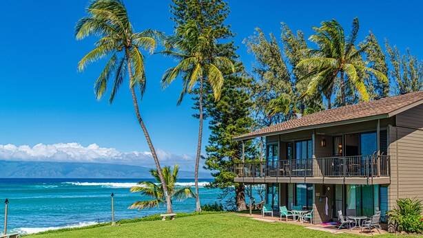 A beachfront hotel with a balcony overlooking the ocean, a lawn, and a view of the sea. - Top floor ocean view 2bd condo (Lahaina)
