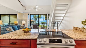 A modern kitchen with a large island, built-in oven, and a view of the outdoors. - Top floor ocean view 2bd condo (Lahaina)