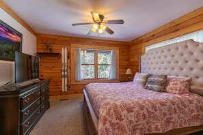 A wooden cabin bedroom with a bed, dresser, skis, and a ceiling fan. - The Heartwood - game room, fire pit, privacy (Linville)