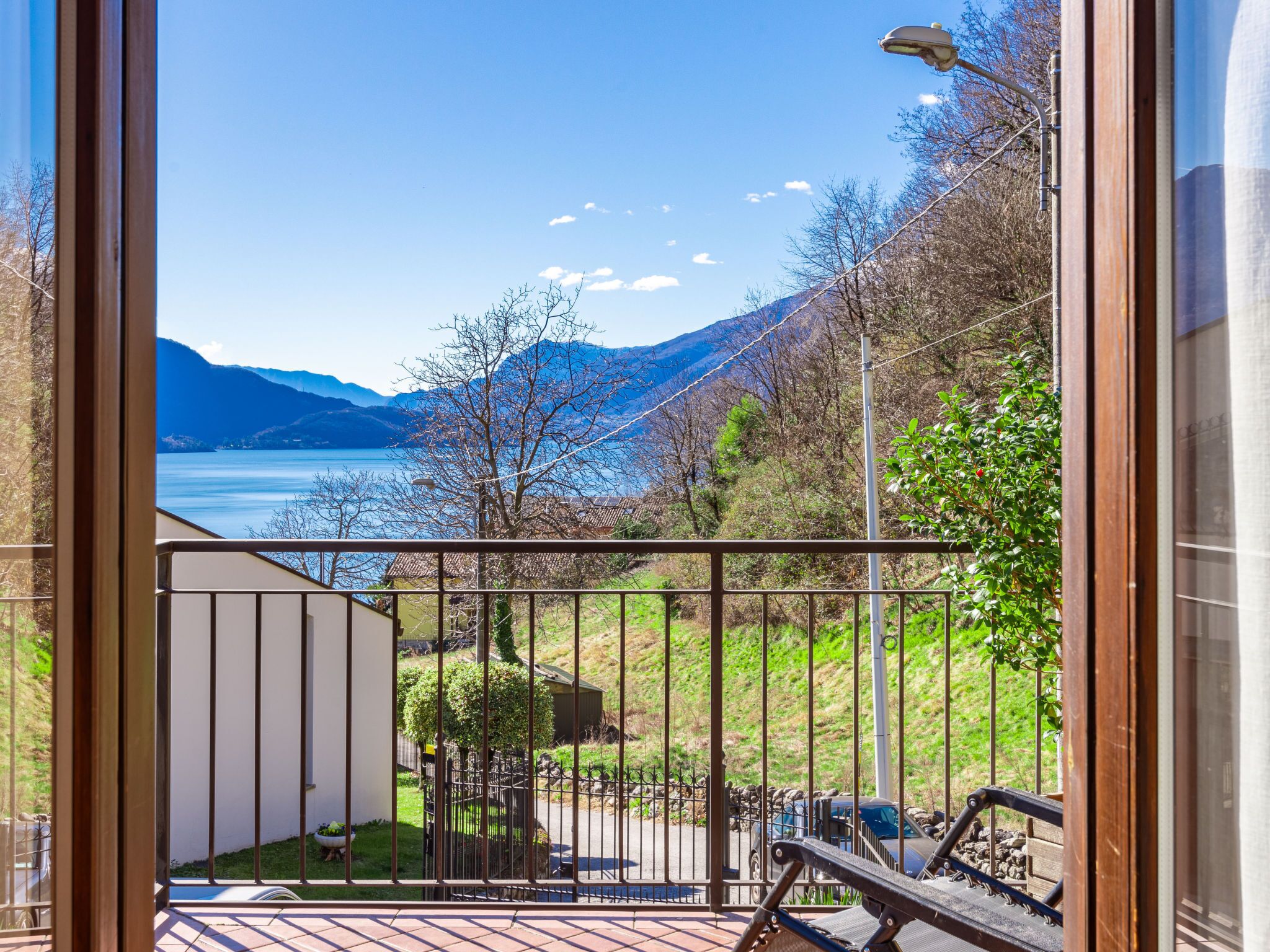 Un balcon offrant une vue sur un lac, des montagnes et un ciel dégagé.