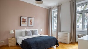 Ein Schlafzimmer mit einem Bett, Nachttischen, einem Fenster mit Vorhängen und Bildern an der Wand.