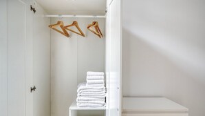 Ein weißer Kleiderschrank mit Kleiderstange und einer Ablage für gefaltete Handtücher.