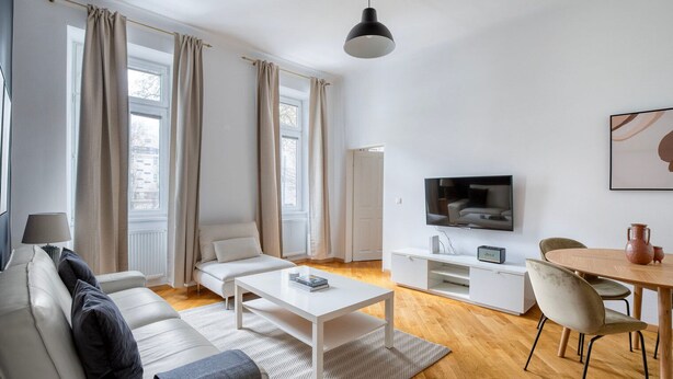Ein modernes Wohnzimmer mit Sofa, Couchtisch, Fernseher und Essbereich.