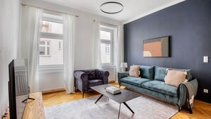 A modern living room with a grey sofa, a coffee table, and a TV.