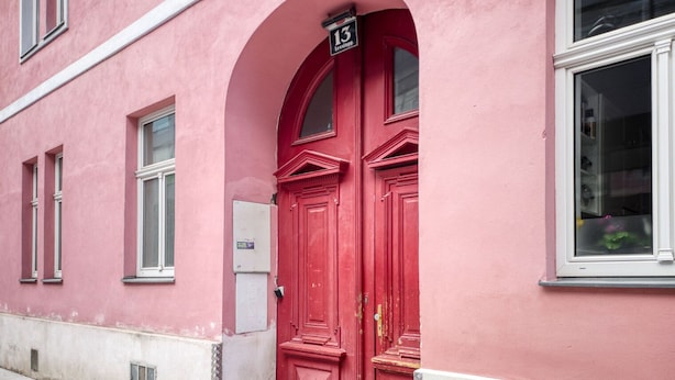 A pink building with a red door and a number 13 sign above it.
