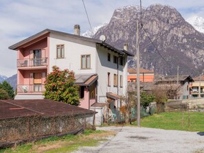 A two-story building with a balcony, a small garden, and a mountain backdrop. - Casa Lara by Interhome (Lago di Mezzola)