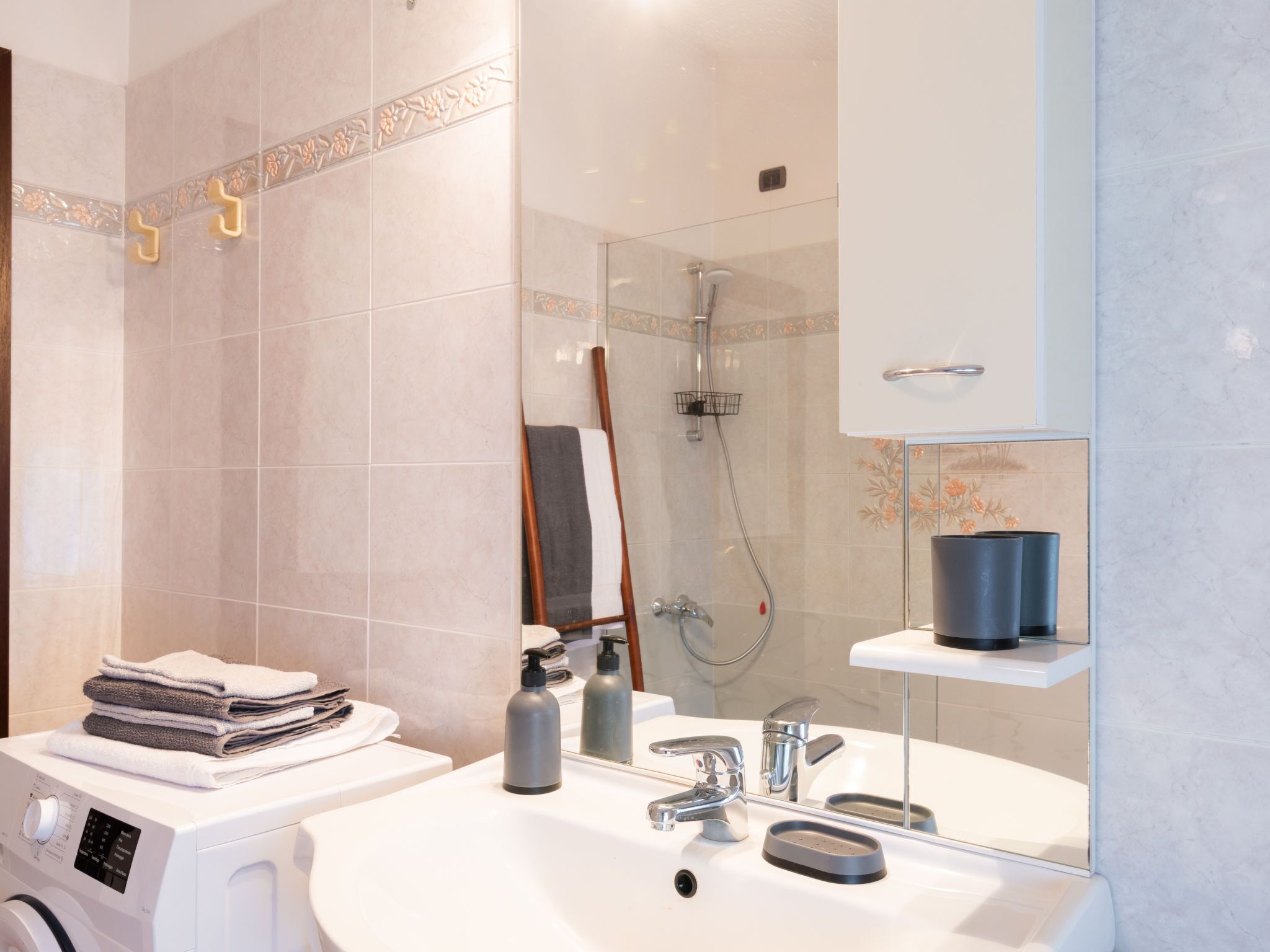 Un baño moderno con lavadora integrada, lavabo con espejo y zona de ducha.
