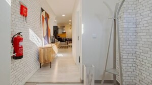 A hallway with white brick walls, a wooden table, a fire extinguisher, and a metal ladder. - Garrett Premium Setúbal (Setúbal)