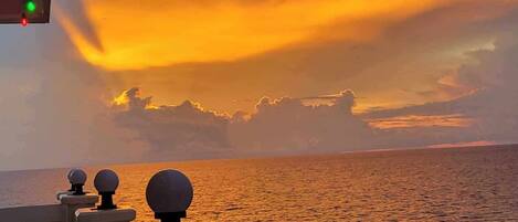 A sunset view from a balcony with a railing and decorative lights.