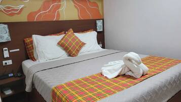 A neatly made bed with a plaid bedspread, white pillows, and a white towel on the side.