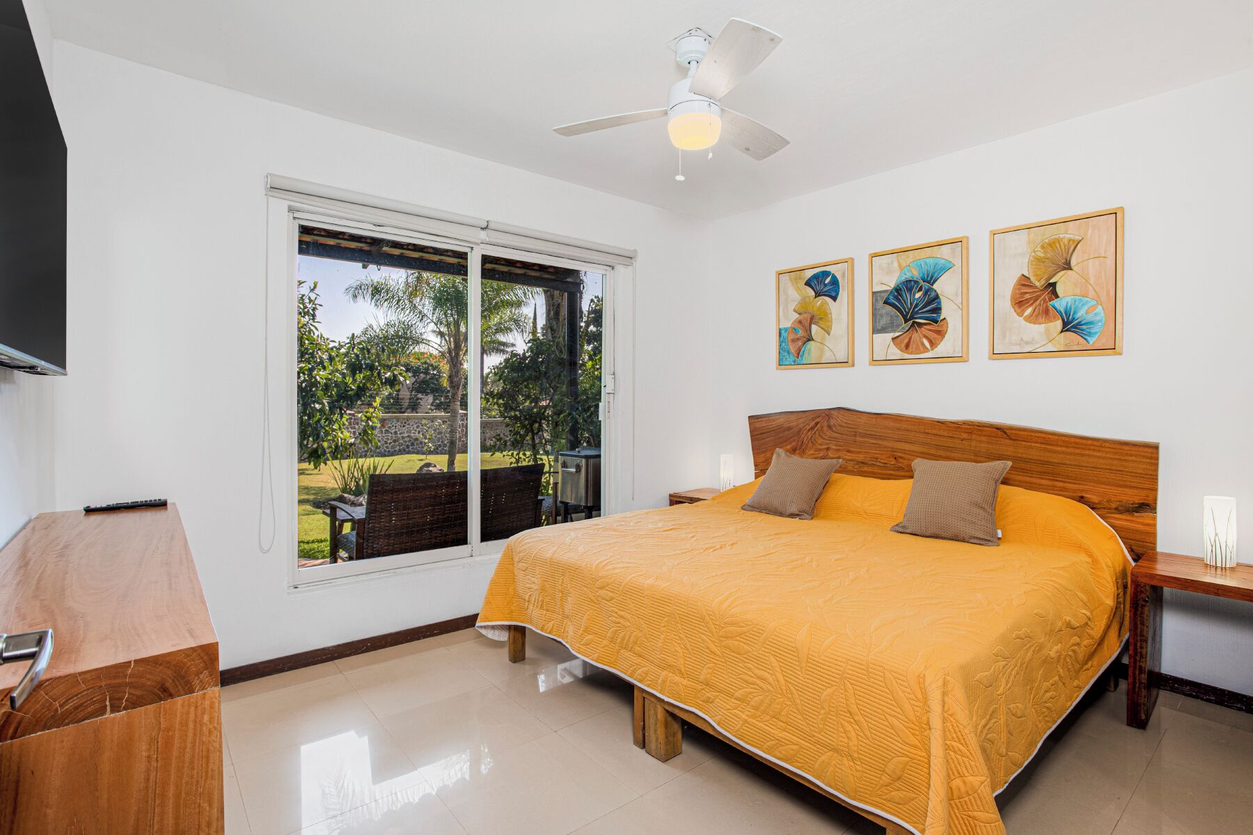 Un dormitorio con una cama grande, un ventilador de techo y una ventana con vistas al exterior.