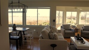 Un salón amplio con un ventanal grande, un comedor con mesa y sillas, y una zona de estar acogedora con sofá y sillones.