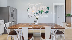 En matplats med ett träbord och vita stolar, ett kylskåp och en vägg dekorerad med ett blommönster.