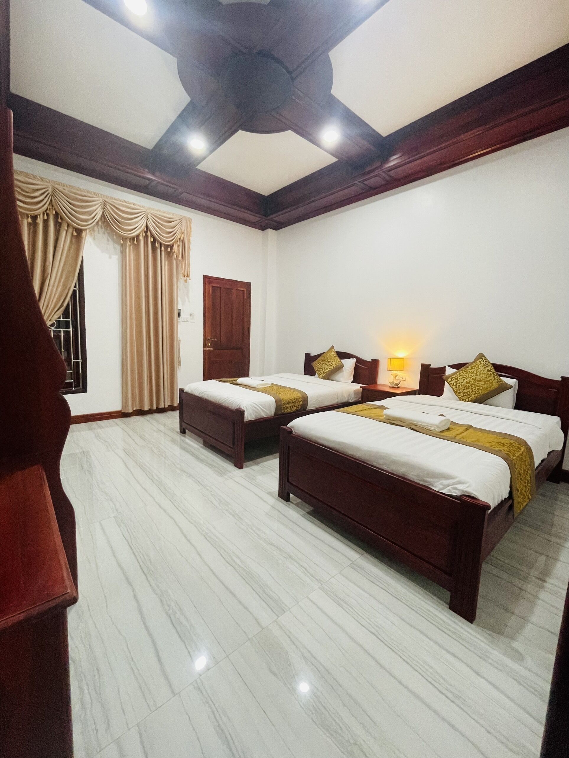 Une chambre d’hôtel avec deux lits, un ventilateur de plafond et une fenêtre avec des rideaux.