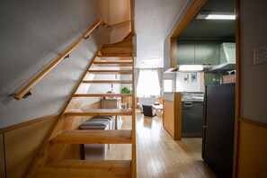 Un escalier en bois mène à une cuisine équipée d’un réfrigérateur et de placards.