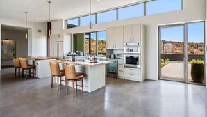 Une cuisine moderne dotée d’un îlot central, de grandes fenêtres et offrant une vue sur l’extérieur.