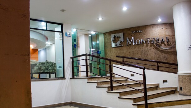 A hotel interior with a staircase, a wall-mounted sign reading "HOTEL MONTREAL," and a glass door leading to another room. - Hotel Montreal  (León)