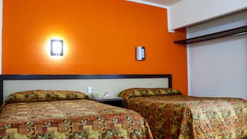 A hotel room with two beds, an orange wall, a nightstand with a phone, and a wall-mounted thermostat.