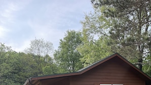 A wooden cabin with a porch and a deck, surrounded by greenery. - Cozy cabin in delightful Wisconsin Dells- Cabin A (Wisconsin Dells)