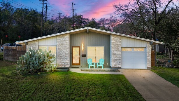 Une maison de plain-pied avec une façade en pierre, une porte d’entrée et un garage.