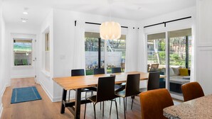 Un espace repas moderne avec une table en bois, des chaises noires et un luminaire suspendu.