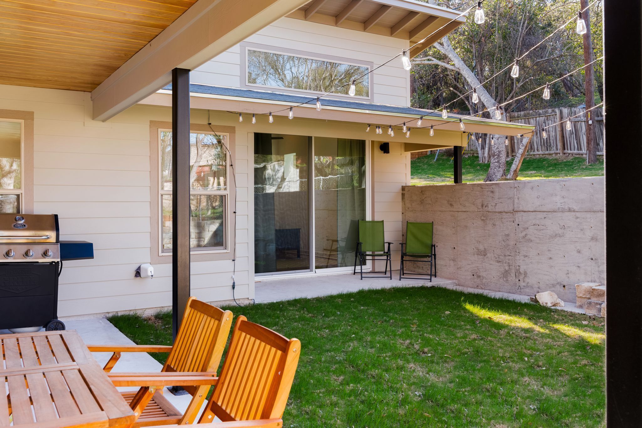 A patio with a grill, outdoor seating, and string lights.