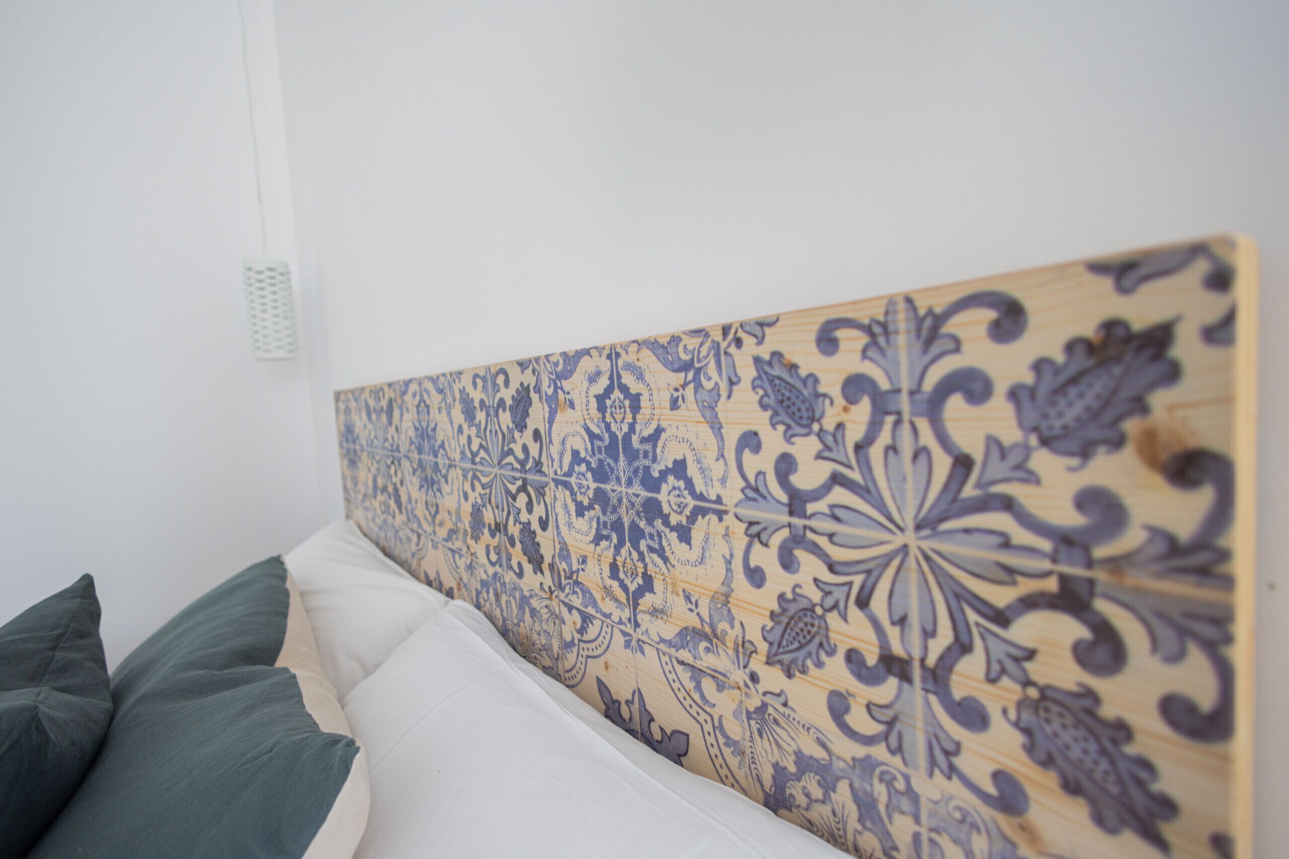A bedroom with a headboard featuring a blue and beige patterned design.