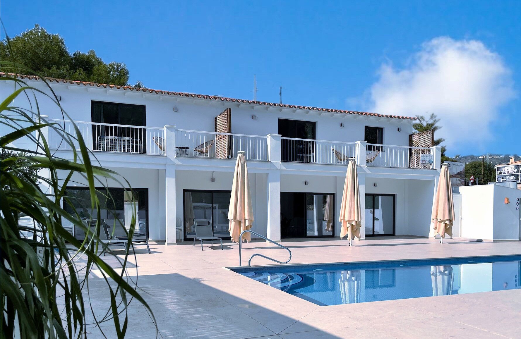 Ein zweistöckiges Gebäude mit Swimmingpool, Außenbereich und einem Balkon.