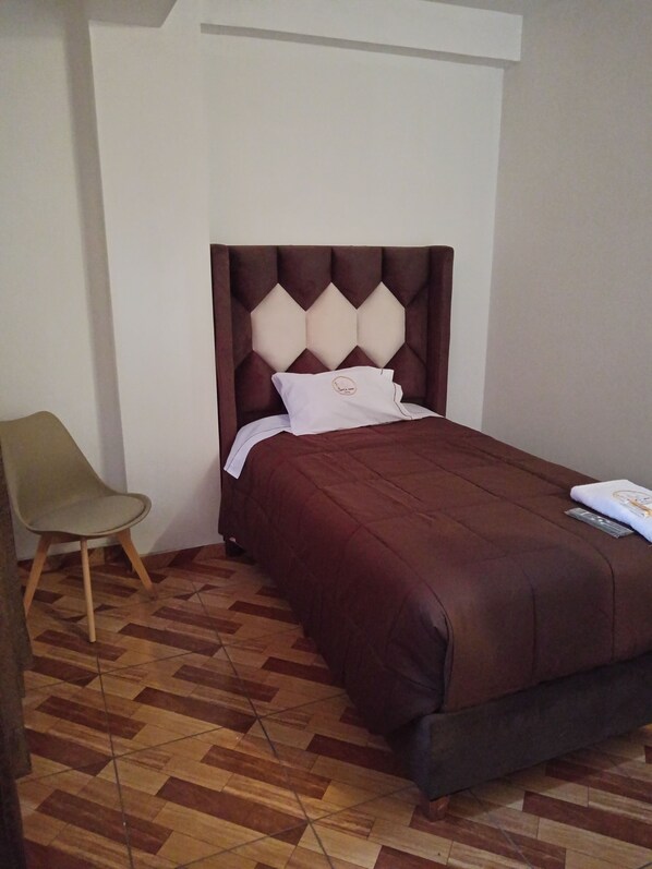 Une chambre à coucher avec un lit, une chaise et un parquet à motifs.