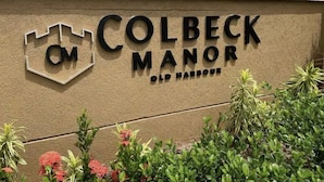 A sign for Colbeck Manor Old Harbour with a logo and text. - Harbour Oasis Retreat - Charming 2 Bedroom House (Old Harbour)