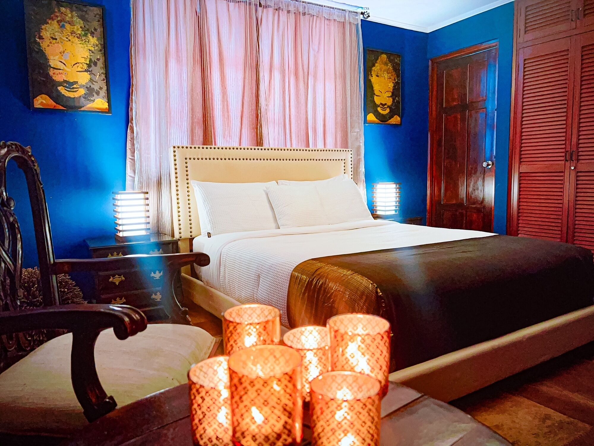 Un dormitorio con cama, mesita de noche, una silla y elementos decorativos.
