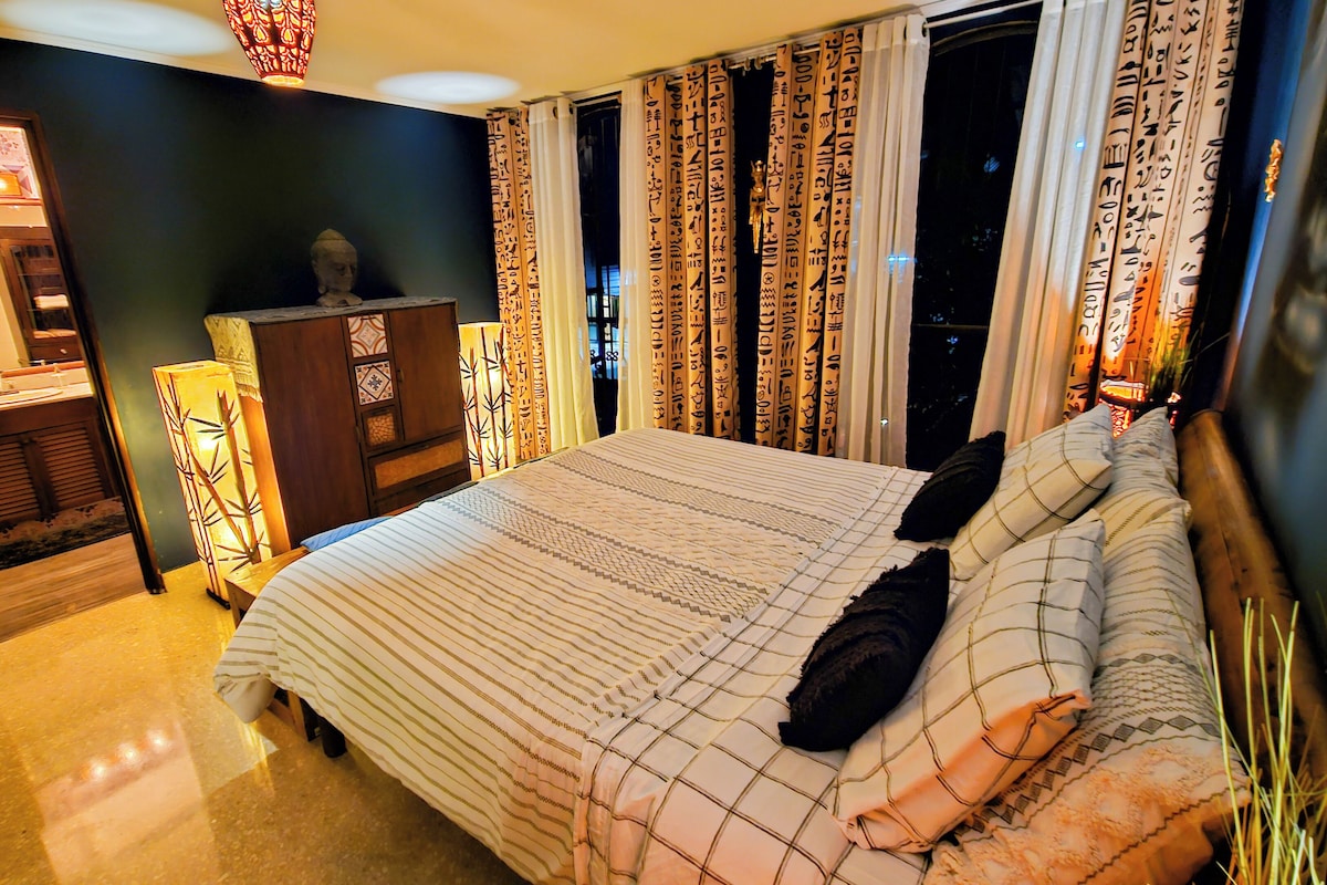 A hotel room with a large bed, a vanity with a mirror, and a cabinet.