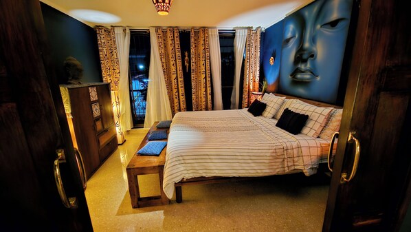 A bedroom with a large bed, a wooden nightstand, a dresser, and a wall mural. - ORHO HOTEL BOUTIQUE PANAMA (Panama City)