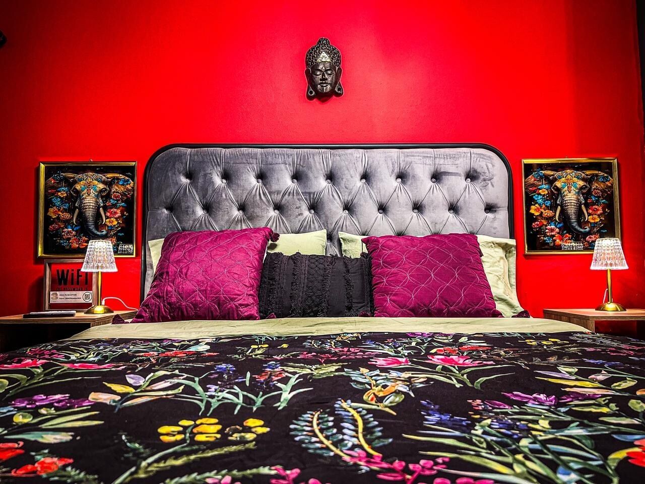 A bed with a tufted headboard, multiple pillows, and a floral-patterned bedspread.