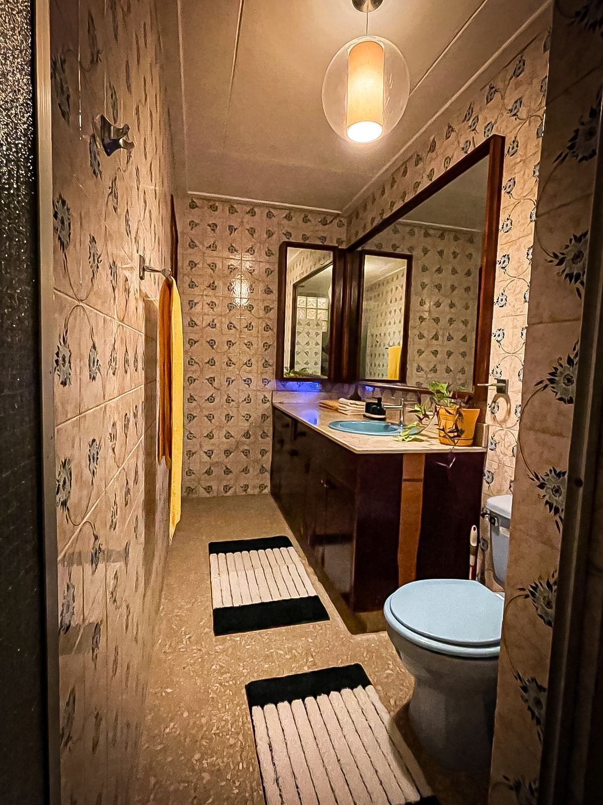 Ein Badezimmer mit Wandmustern, einem Spiegel, einem Waschbecken und einer Toilette.