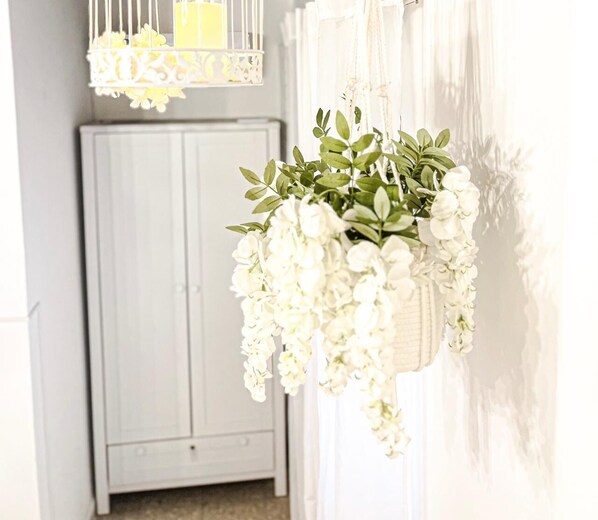 Una maceta colgante blanca con flores blancas y hojas verdes.