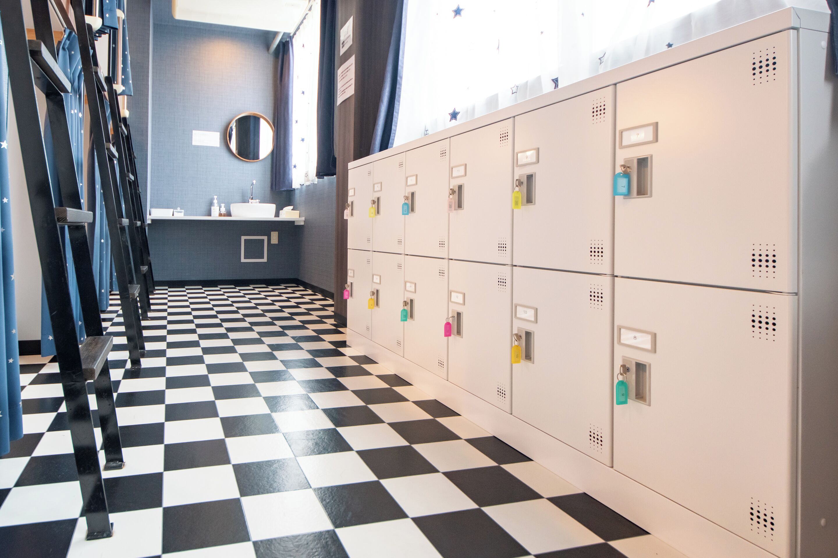 A locker room with a checkered floor, lockers, a sink, and a mirror.