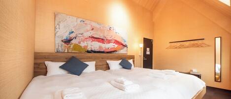 Un dormitorio amplio con una cama grande, un cabecero de madera y un cuadro en la pared superior.