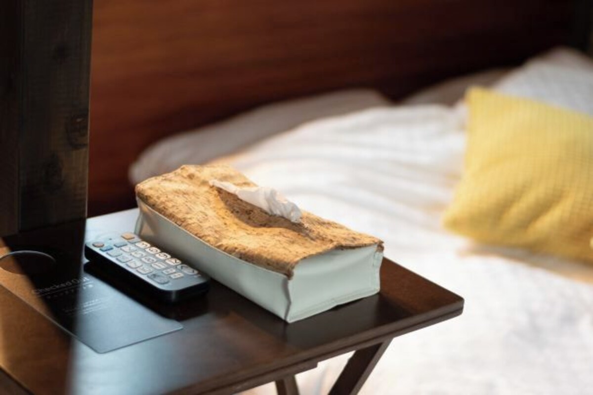 A bedside table with a remote control and a tissue box.