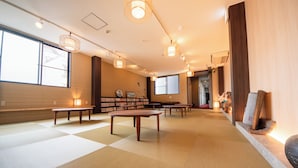A spacious room with tatami mats, wooden tables, and a bookshelf. - Hotel Base Nara (Nara)