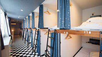 Una habitación de hotel con literas, piso a cuadros y cortinas azules con motivos de estrellas.