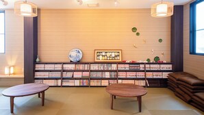 A modern library with wooden bookshelves, two tables, and decorative wall art. - Hotel Base Nara (Nara)